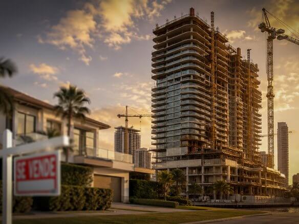 Edificio residencial en construcción en Miami que representa la inversión de capital bajo el programa EB-5, contrastado con una casa en venta tradicional